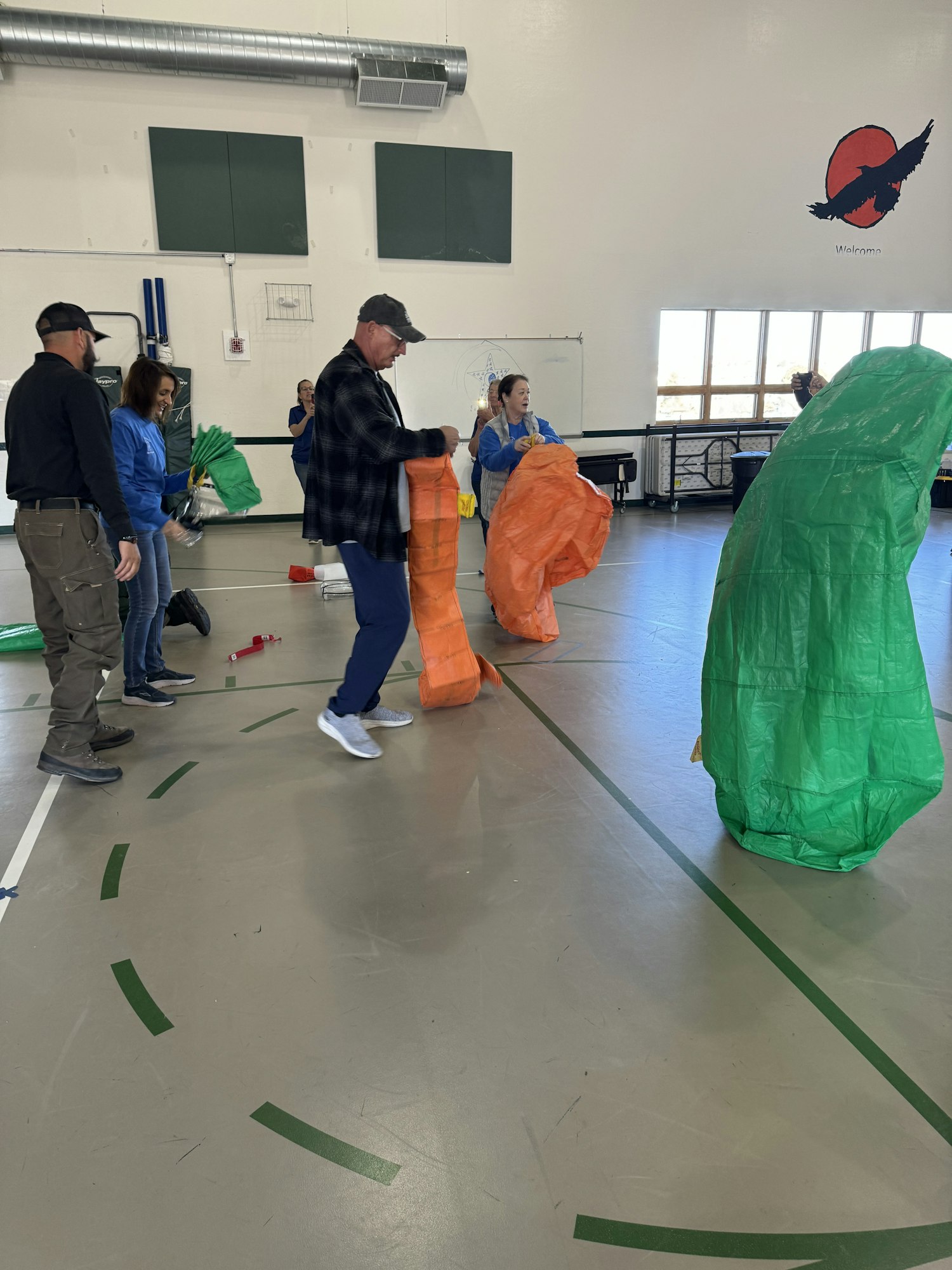 People indoors with colorful bags, possibly setting up or engaging in an activity.