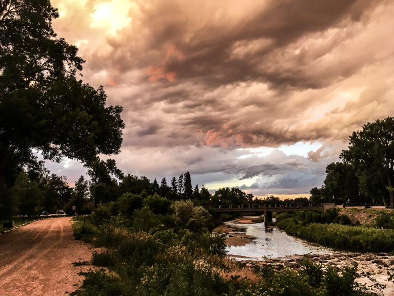 Image containing view of the landscape near Fountain Creek including sky with clouds, creek to the right, and dirt path on the left
