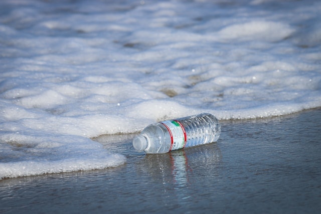 Plastic bottle on a beach with incoming foam waves