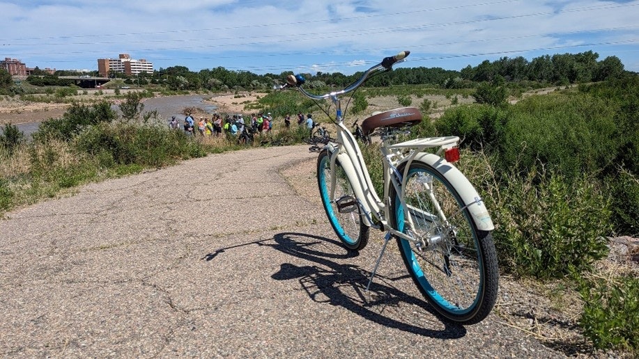 Bicycle by a path, people in the distance, greenery, and a river.