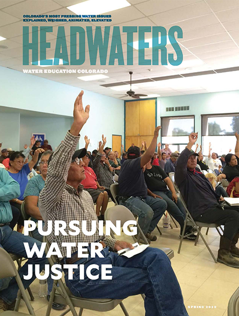 Magazine cover featuring a group of people raising their hands in a meeting, titled "Pursuing Water Justice."