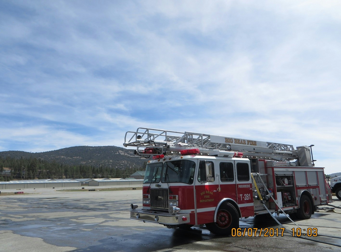 A fire truck with a ladder from the Big Bear Fire Department parked outdoors under a clear sky.