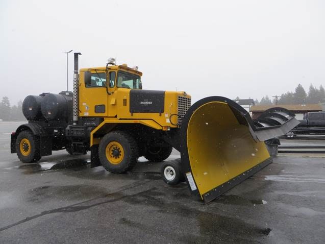 A yellow snow plow truck in a snowy environment.