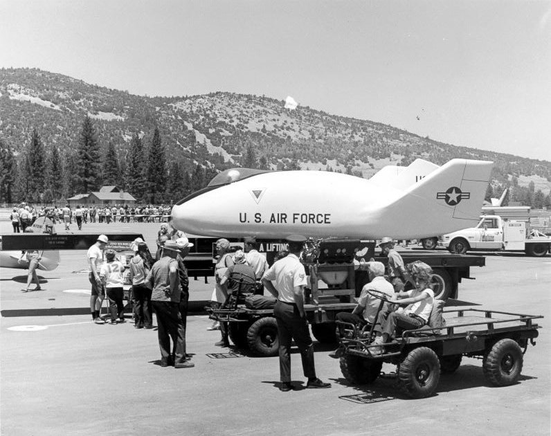 People gather around a U.S. Air Force lifting body aircraft on display outdoors.