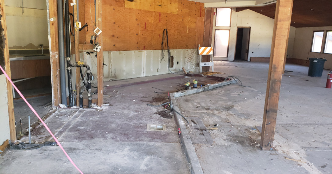 An unfinished or under-renovation space with exposed wiring and plumbing. Construction materials and equipment scattered around.