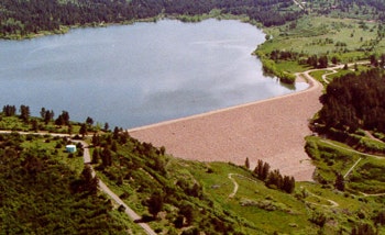 Aerial view of a lake with surrounding trees and pathways, possibly a park or recreational area.
