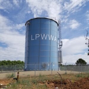 A large blue water storage tank with "LPWWA" on it, surrounded by a fence under a cloudy sky.