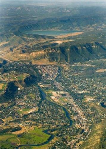 Aerial view of a town with roads and houses nestled between green hills and a nearby lake.
