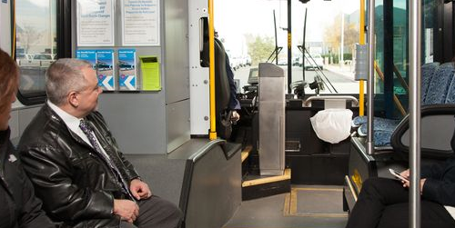 Man on a bus looking toward the front, with a view of the farebox.