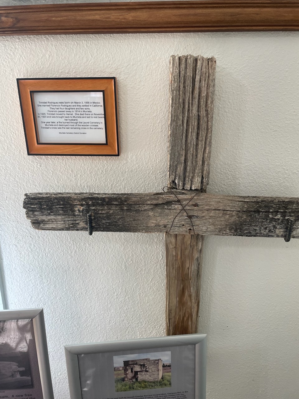 A framed text about Trinindad Rodriguez and a wooden cross on a wall.