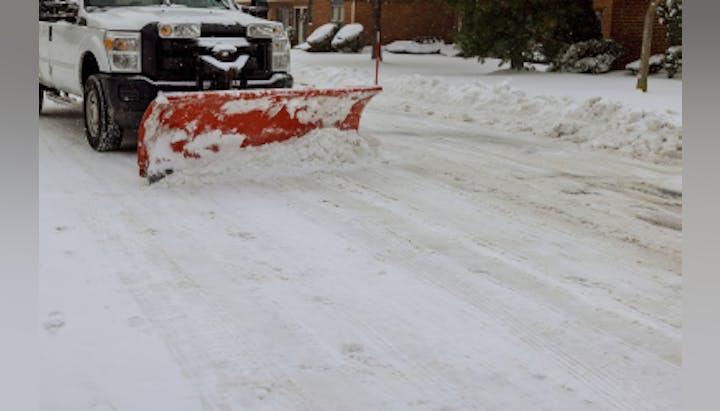 A snowplow truck clearing snow from a residential street.