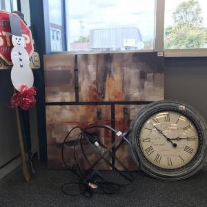 Painting, large clock, coiled cables, and snowman decoration by a window.