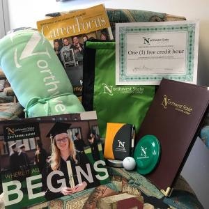Northwest State items: blanket, magazines, certificate for one free credit hour, and a folder, all arranged on a chair.