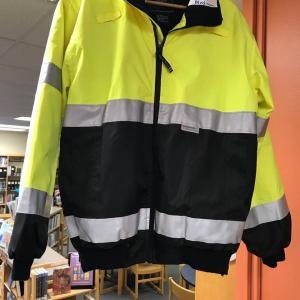 A yellow and black high-visibility jacket with reflective stripes, hanging indoors.