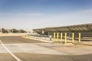 Solar panels in a desert landscape, mounted on angled structures with a clear blue sky.
