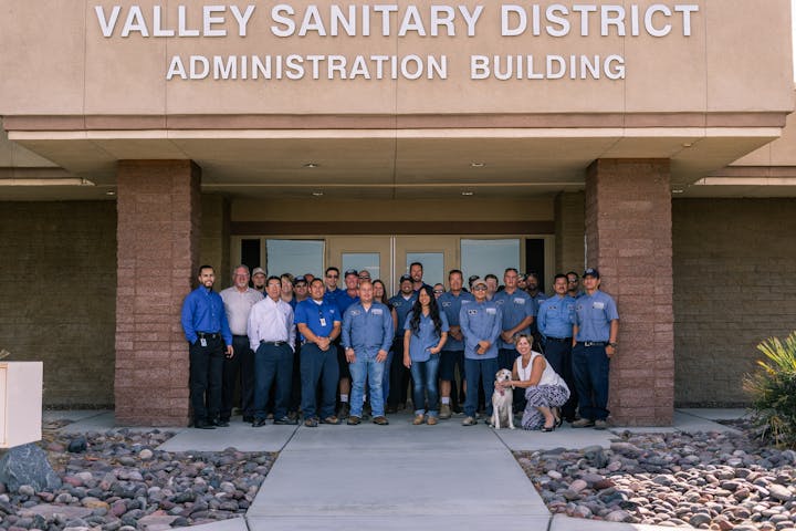 Group of people and a dog in front of the Valley Sanitary District Administration Building.
