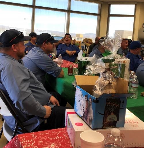 People sitting around decorated tables with gift boxes and drinks.