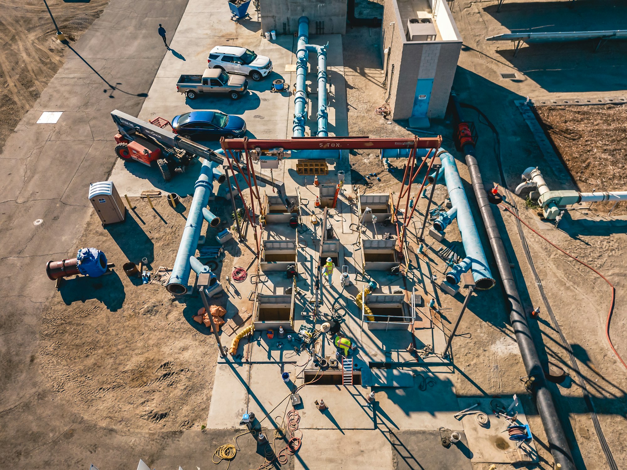 Construction site with vehicles, large pipes, and workers in an organized area.