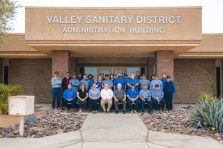 A group of people pose in front of the Valley Sanitary District Administration Building.
