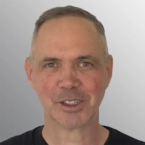 A man with short hair and a slight smile against a plain background.