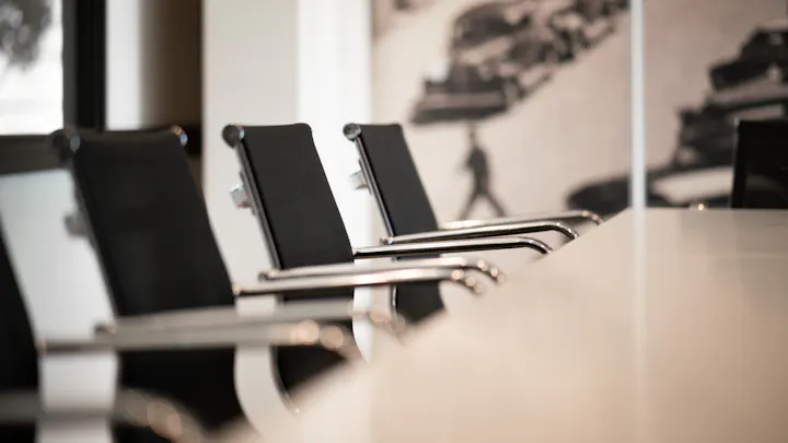 The image shows a close-up of modern black chairs in a conference room with a minimalist design.