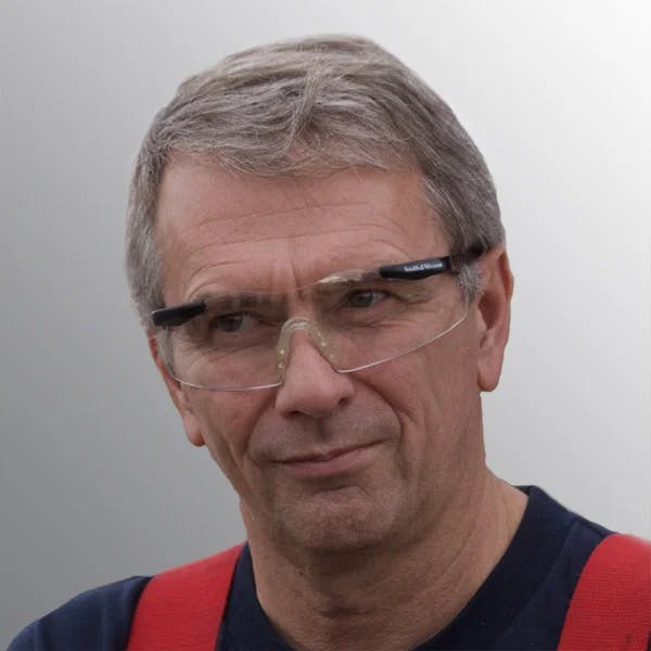 A person wearing safety glasses and a red strap, with a neutral expression.