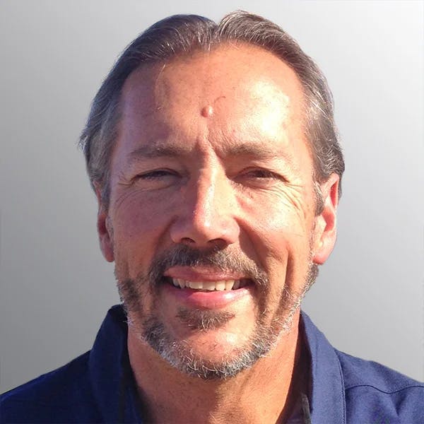 I don't know who this is, but the image shows a smiling man with short hair and a beard against a plain background.