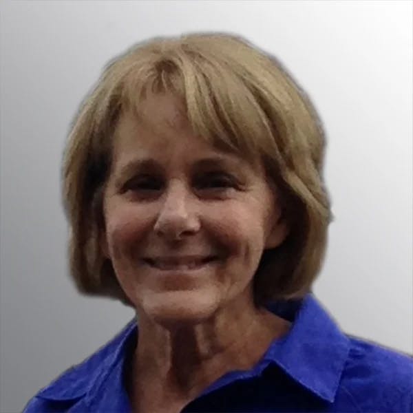 A person with short hair smiling, wearing a blue shirt.