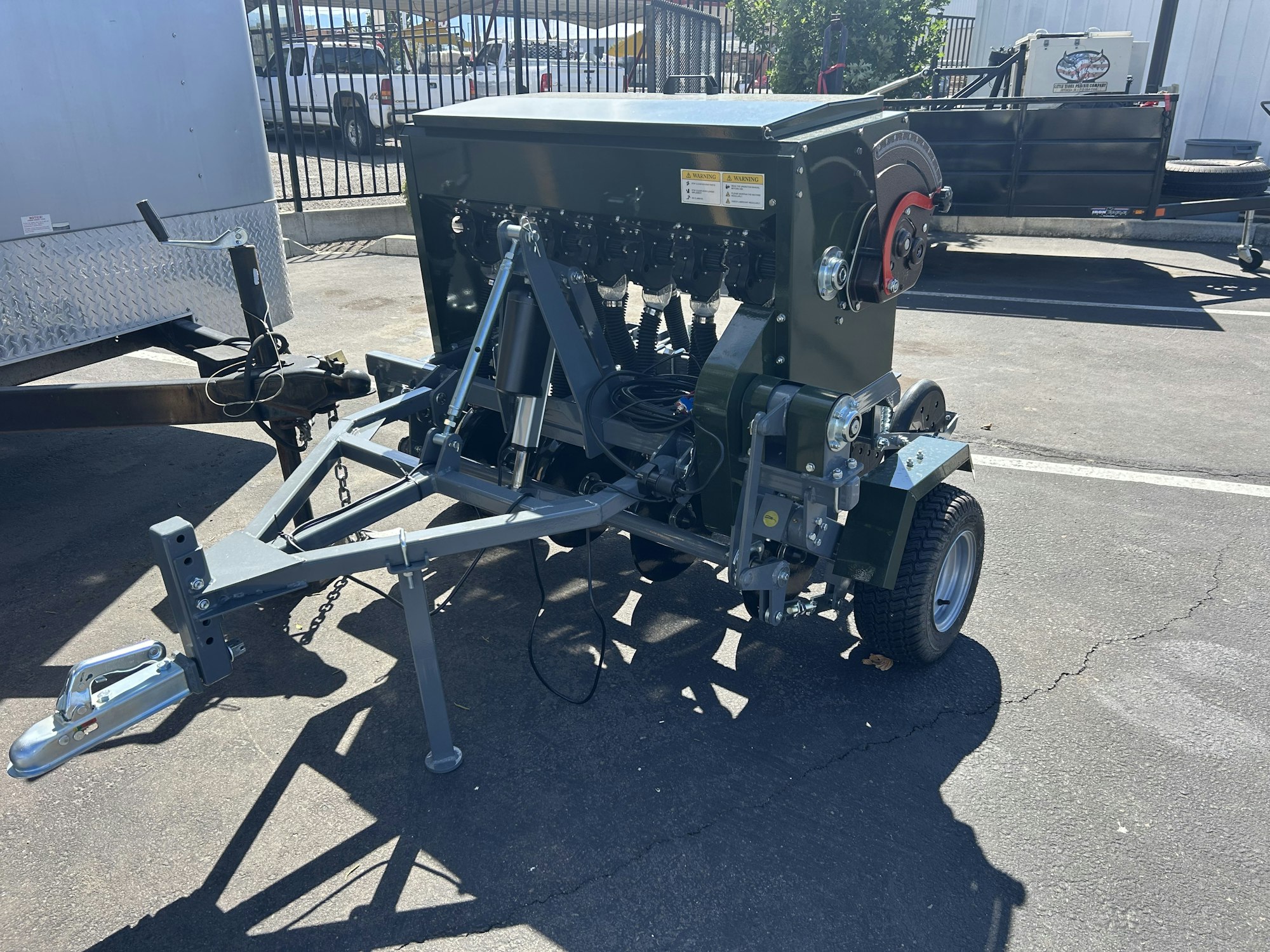 A portable trailer-mounted utility unit with cables and mechanical components, positioned in a parking lot.