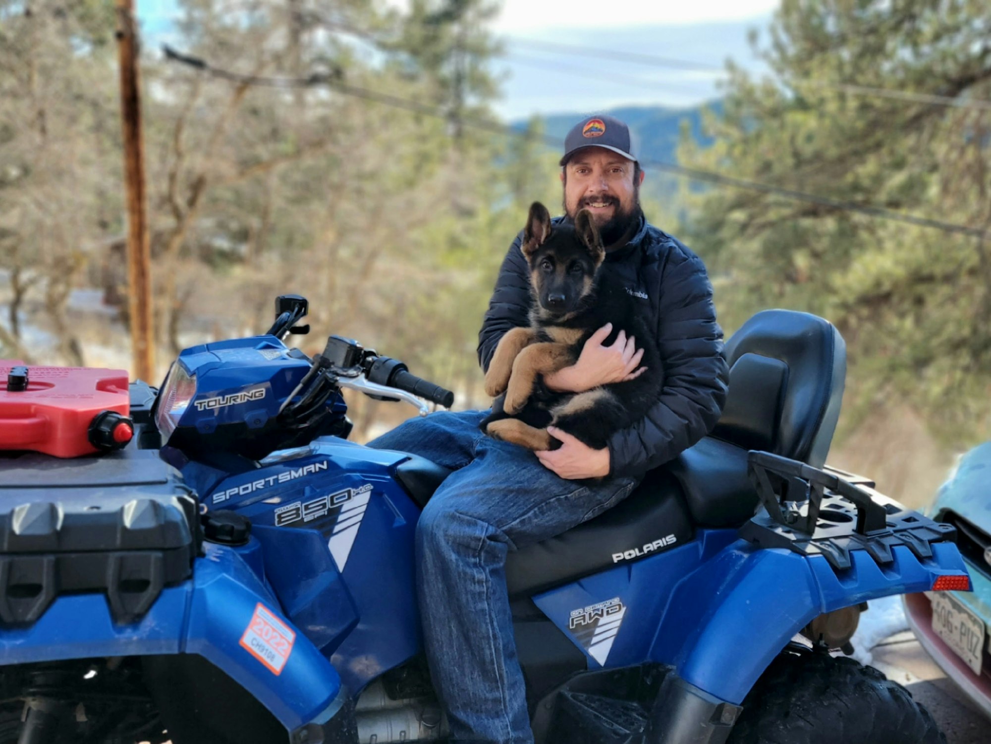 May contain: clothing, pants, face, head, person, photography, portrait, helmet, animal, canine, dog, mammal, pet, puppy, adult, male, man, hardhat, coat, jacket, atv, transportation, vehicle, and jeans