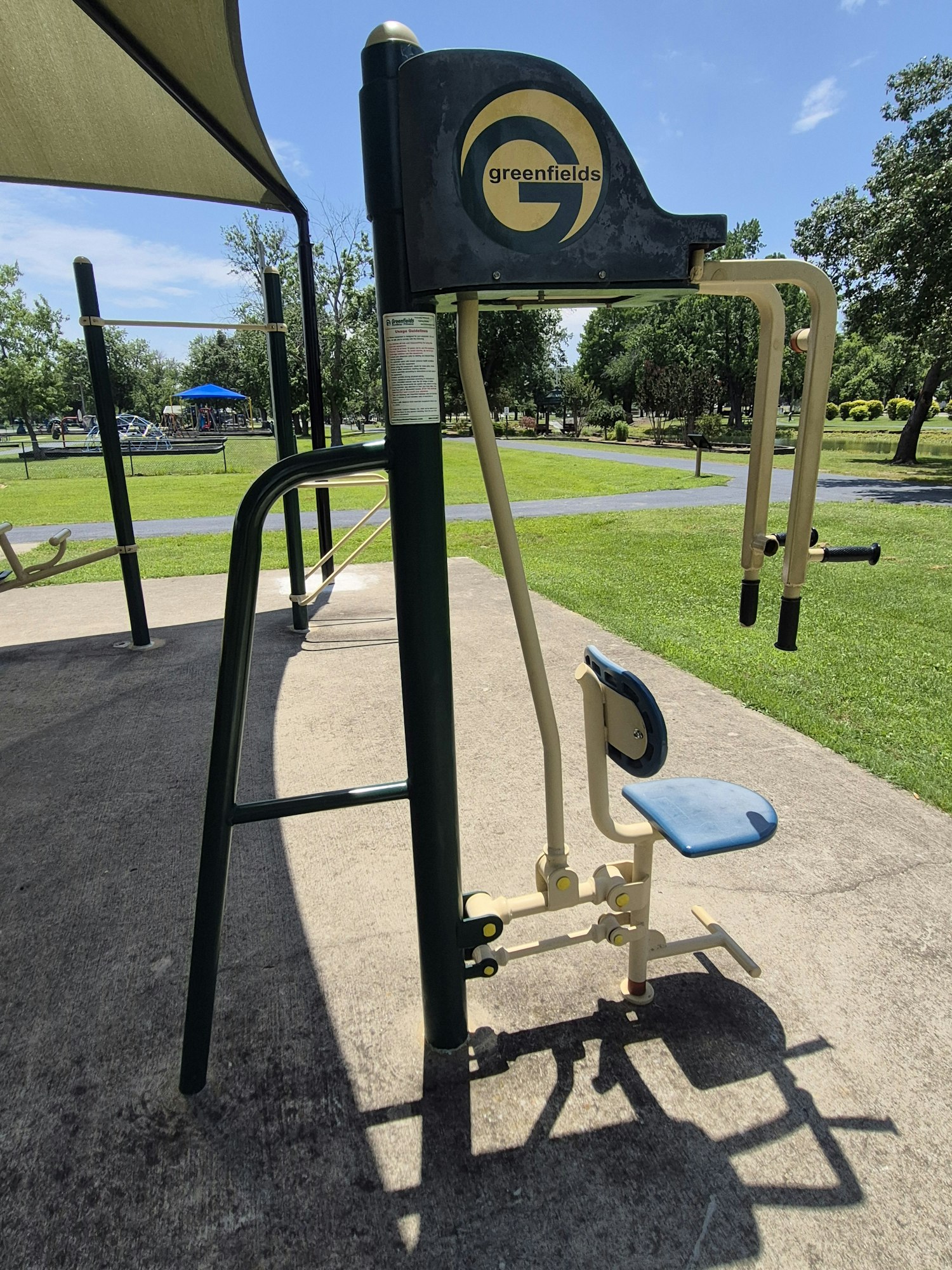 An outdoor exercise machine for fitness, located in a park with green grass and blue skies in the background.