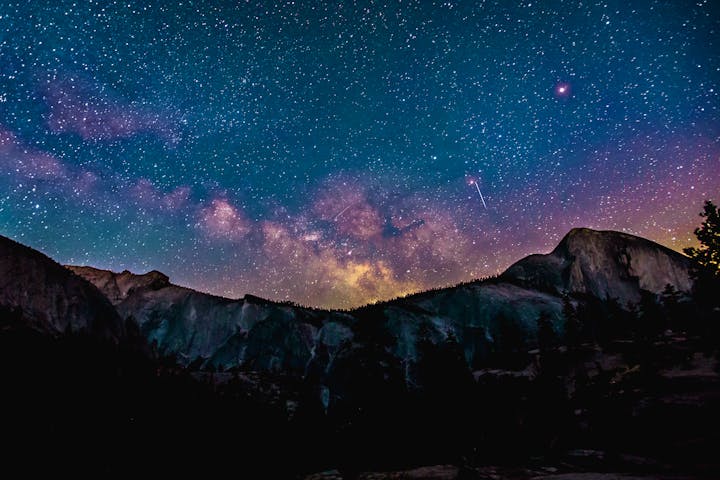 Starry night sky over silhouetted mountains, featuring the Milky Way.