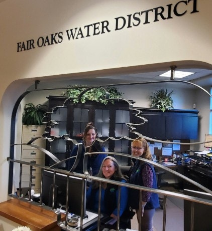 Three people at the Fair Oaks Water District office, smiling at the camera.