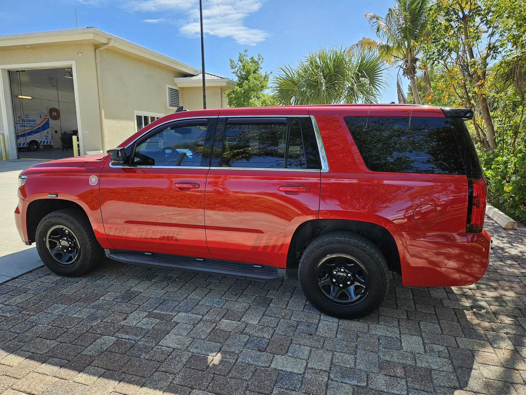 A red SUV parked outside a building with palm trees in the background.