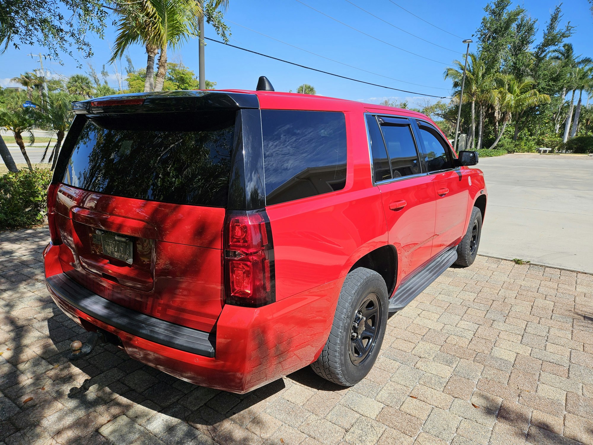 A red SUV parked on a sunny day, with palm trees in the background.