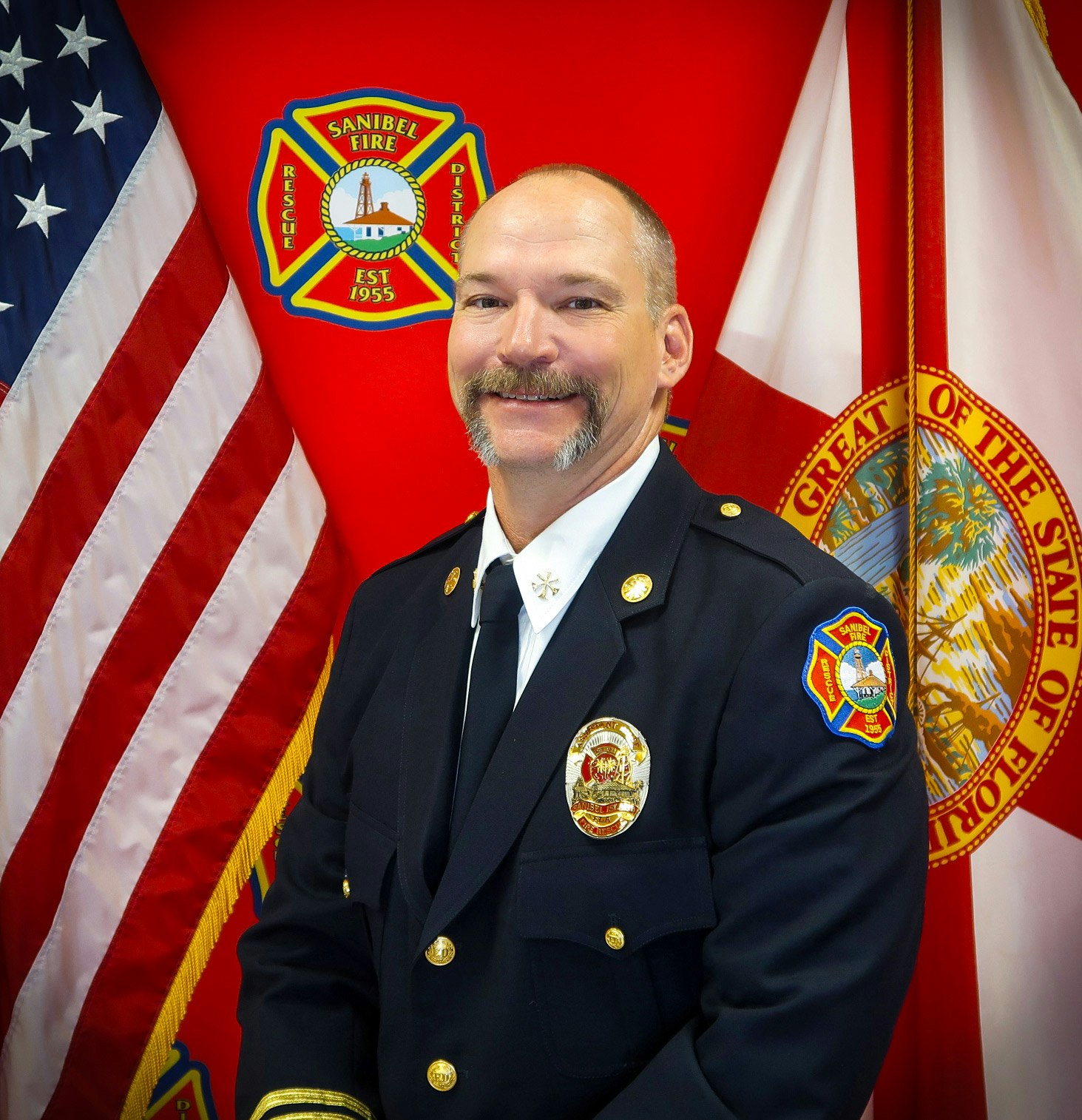 Fire department officer in uniform, standing before the American and Florida flags.