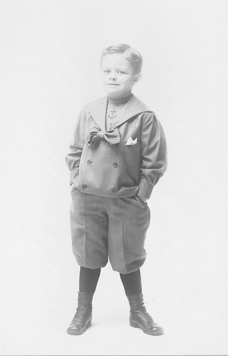May contain: photography, face, head, person, portrait, boy, child, male, clothing, coat, standing, footwear, shoe, jacket, and sailor suit