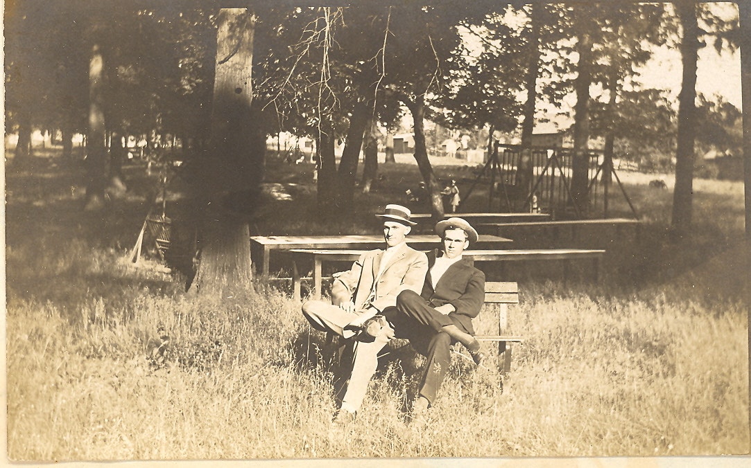 May contain: bench, furniture, person, reading, sitting, clothing, hat, adult, male, man, grass, plant, and people