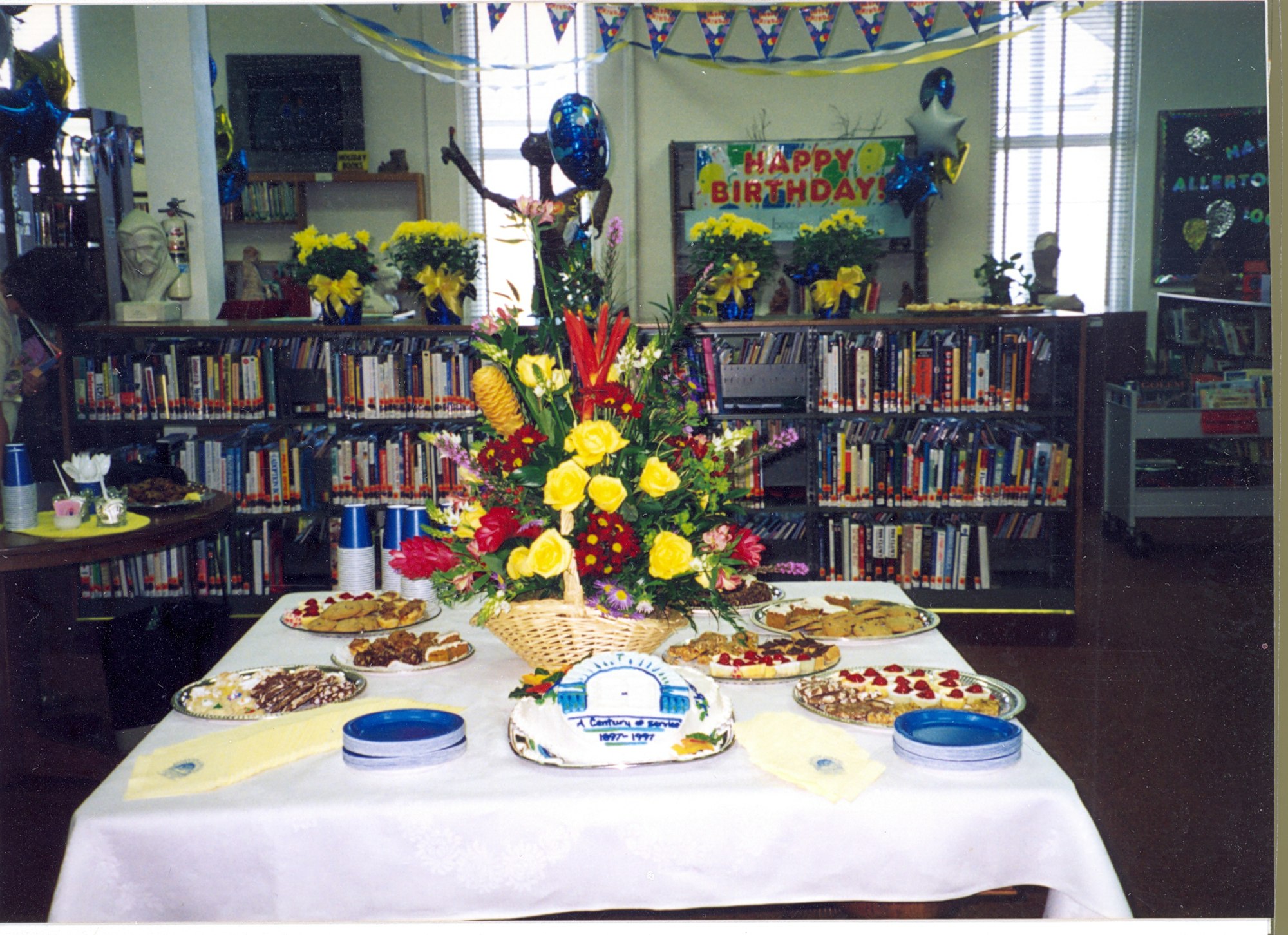 May contain: flower, flower arrangement, plant, cafeteria, indoors, restaurant, dining table, furniture, table, food, meal, flower bouquet, architecture, building, dining room, room, book, library, and publication
