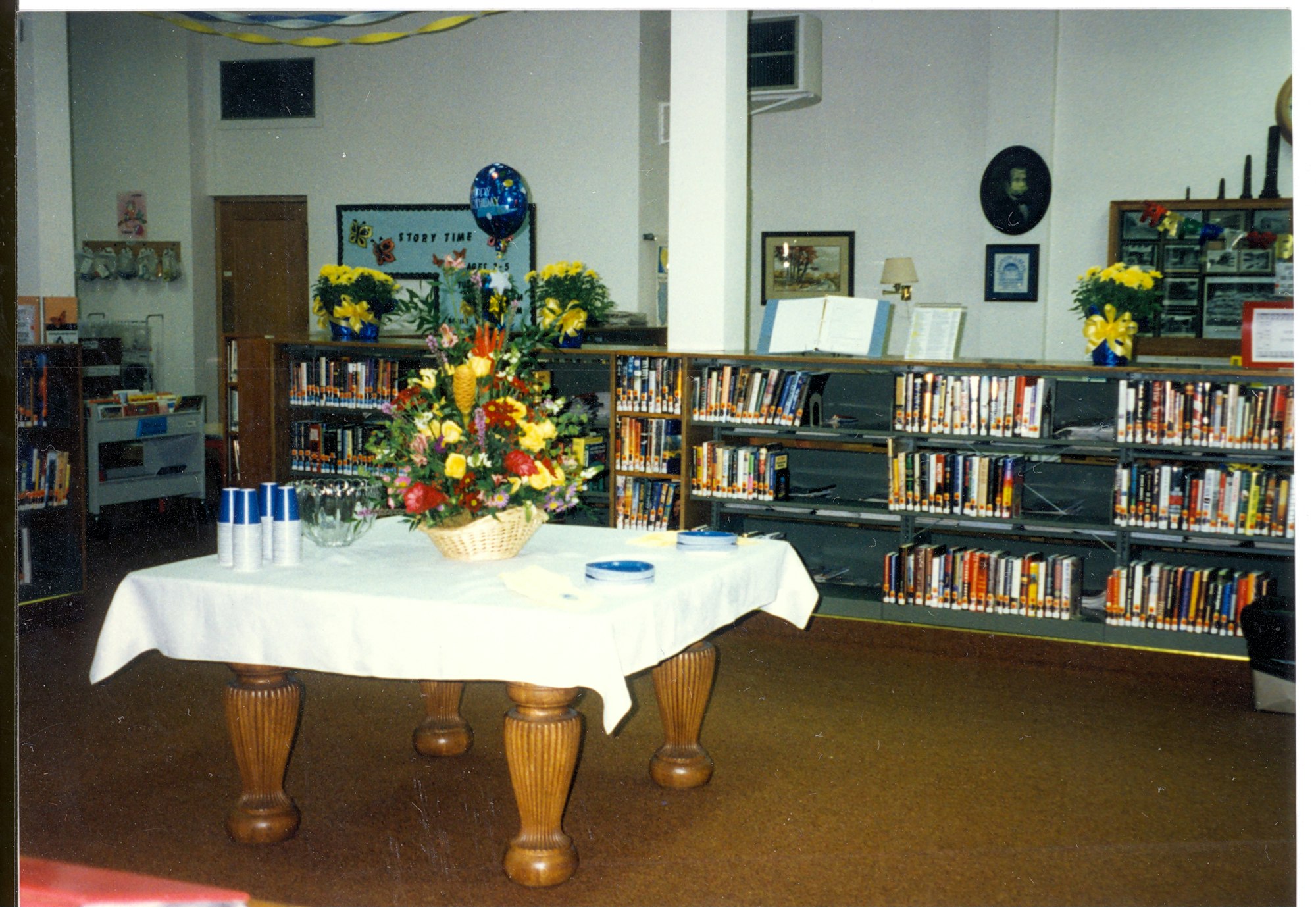 May contain: flower, flower arrangement, plant, flower bouquet, book, indoors, library, publication, architecture, building, wood, shelf, plywood, furniture, table, interior design, floor, and flooring