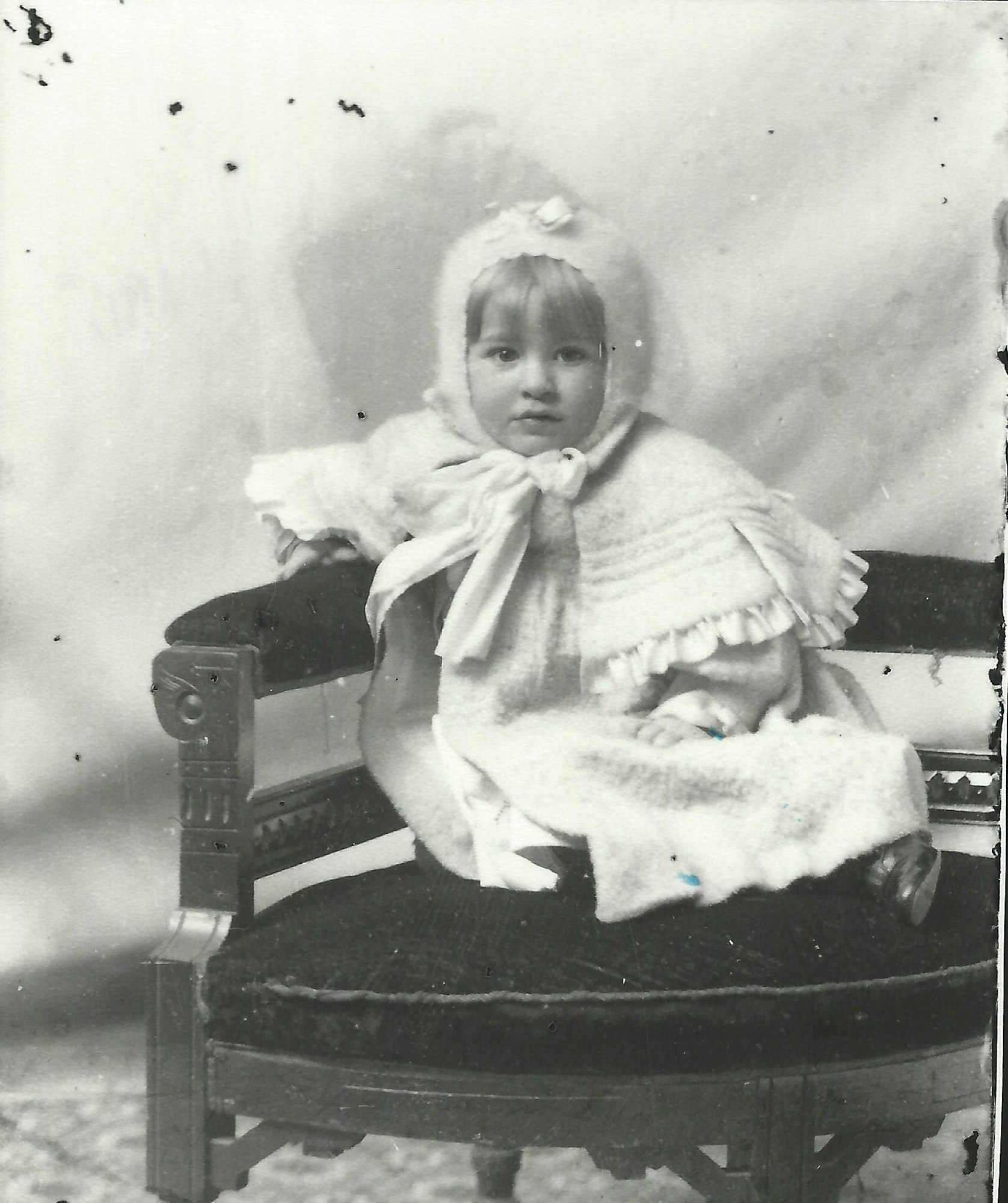 May contain: clothing, hat, face, head, person, photography, portrait, bonnet, furniture, and baby