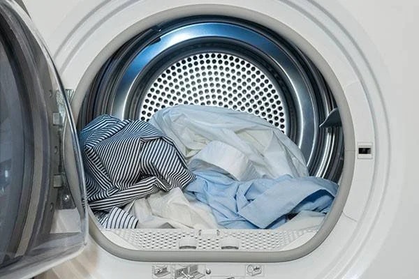 Open dryer with striped and blue shirts inside.