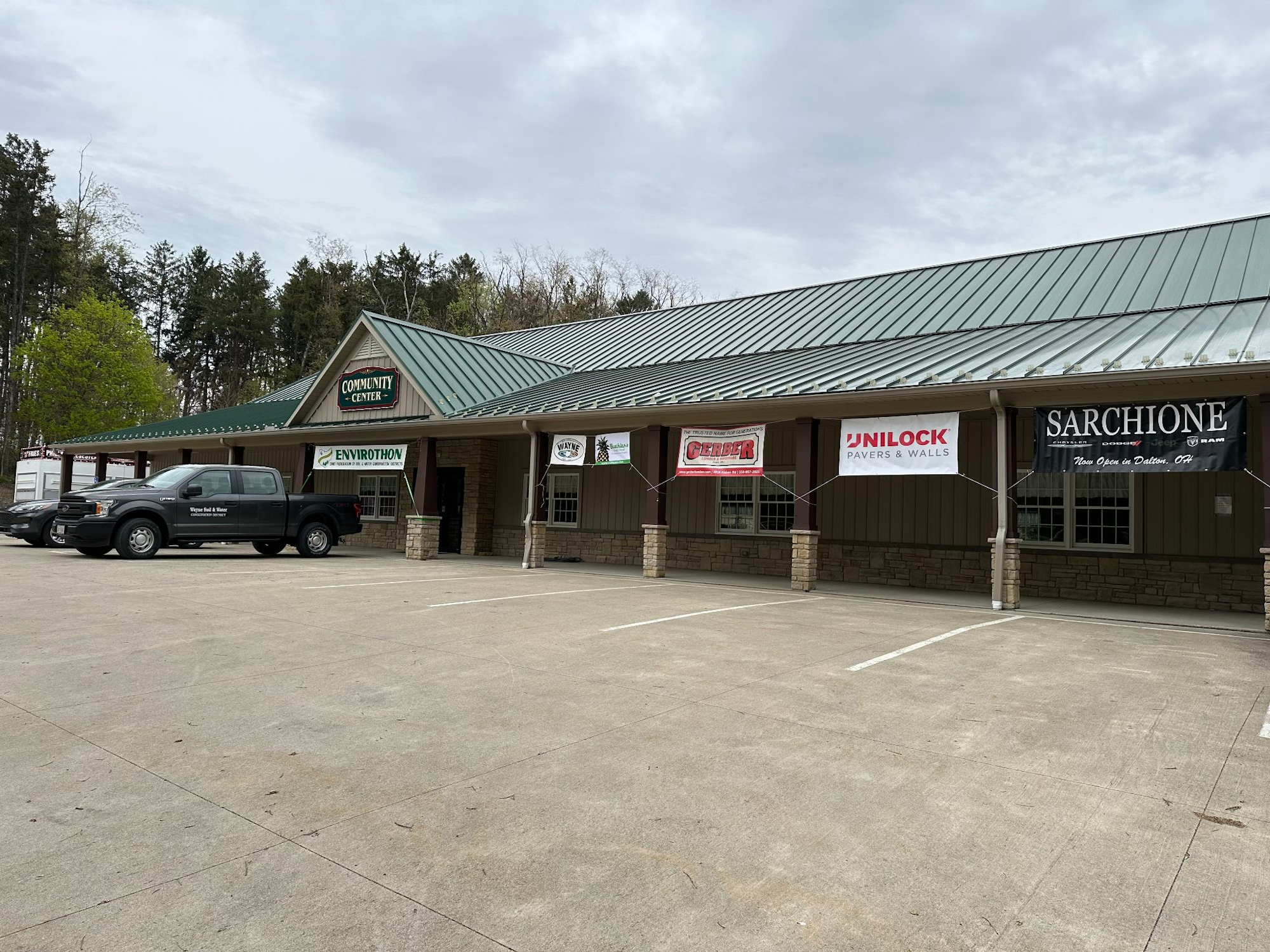 A community center with a truck parked outside and banners for various companies displayed on the building.
