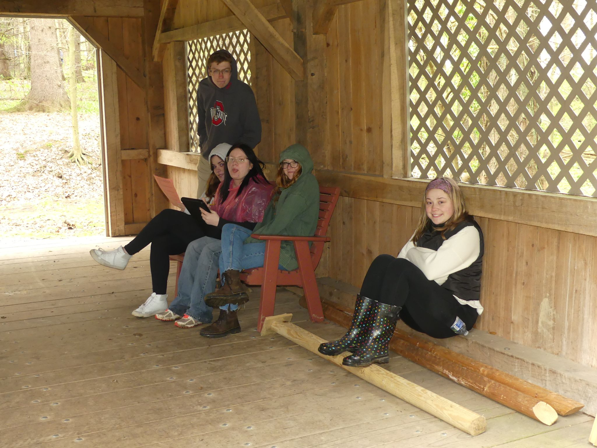 Five people seated in a wooden structure, dressed warmly.