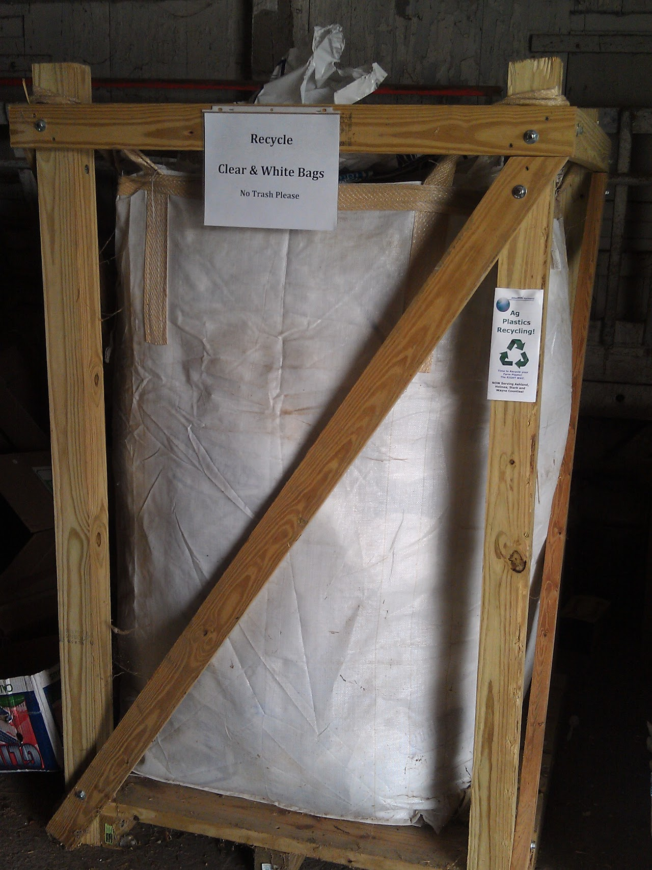 Wooden frame holding a large white bag for recycling clear and white bags, labeled "No Trash Please" with an "Ag Plastics Recycling" sticker.