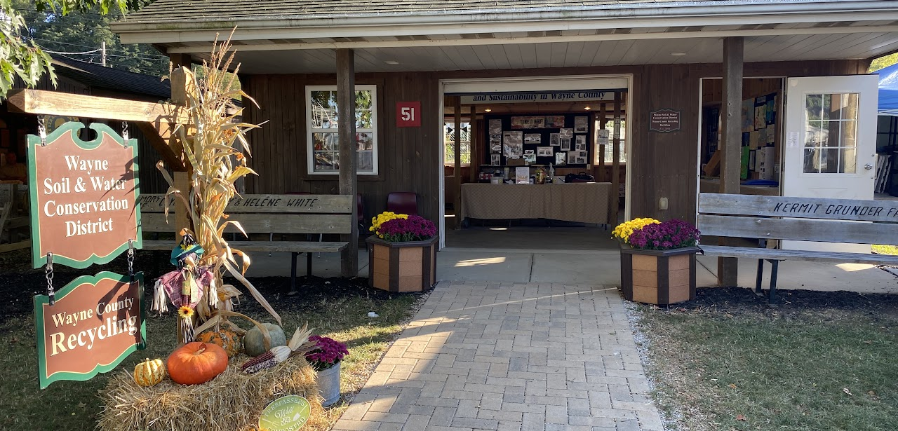 A wooden building labeled Wayne Soil & Water Conservation District, with fall decor, benches, and signs for Wayne County Recycling.