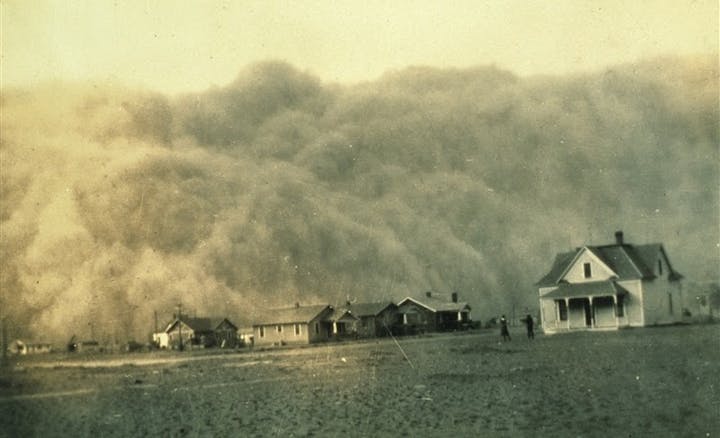 A massive dust storm approaching a row of houses on a flat landscape.