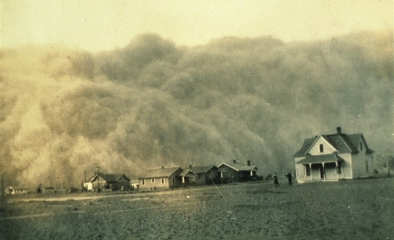 A massive dust storm approaching a row of houses on a flat landscape.
