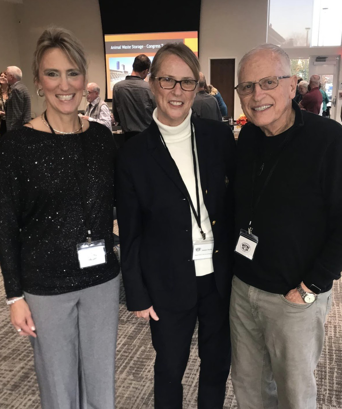 Three people posing and smiling at a conference or event.