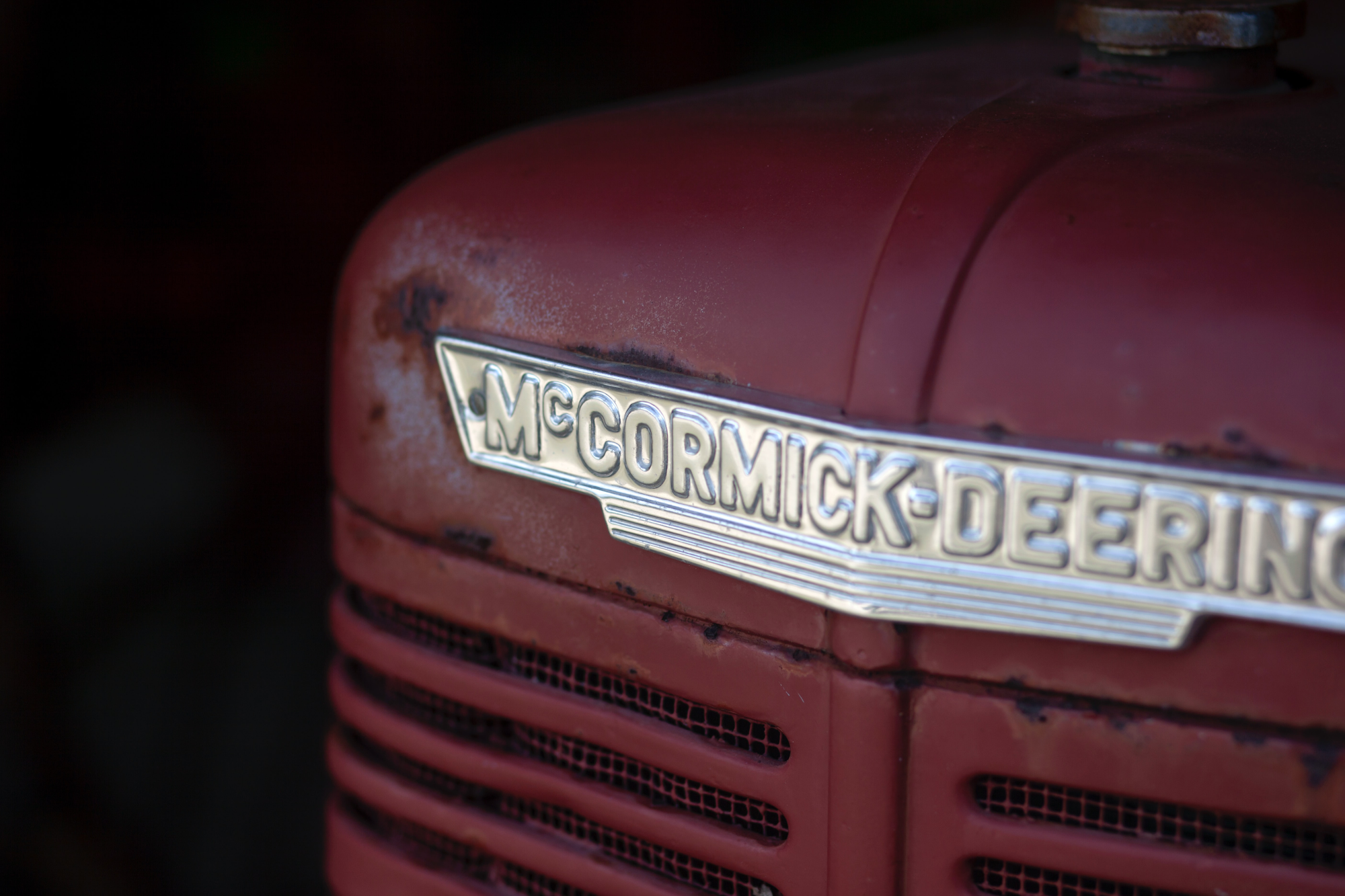 Close-up of a vintage McCormick-Deering tractor badge on a rusty red surface.
